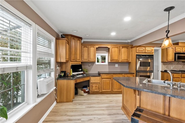 kitchen featuring sink, decorative light fixtures, built in desk, stainless steel appliances, and light hardwood / wood-style floors