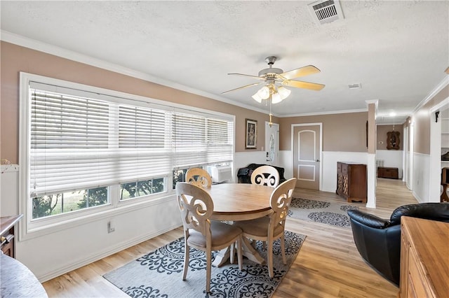 dining space featuring ceiling fan, ornamental molding, a textured ceiling, and light wood-type flooring