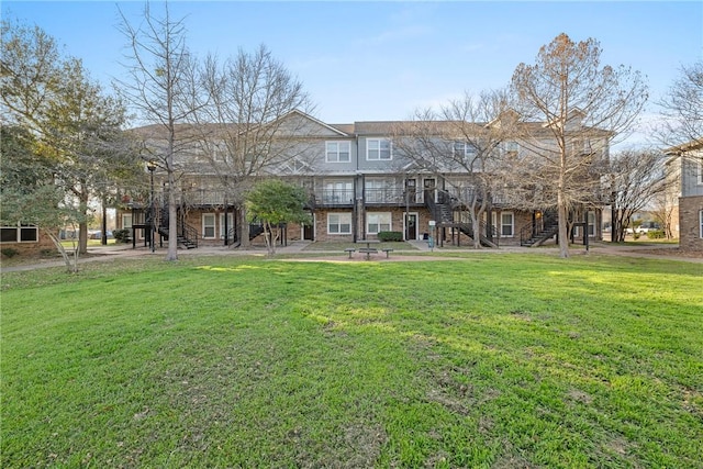 back of house with a patio area, stairway, brick siding, and a yard