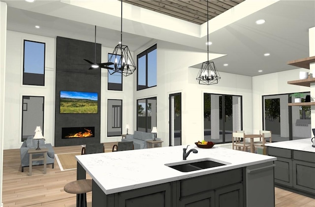 5371 Legend Oaks Ct, College Station, TX 77845 - kitchen featuring gray cabinetry, open floor plan, light wood-type flooring, a chandelier, and a towering ceiling