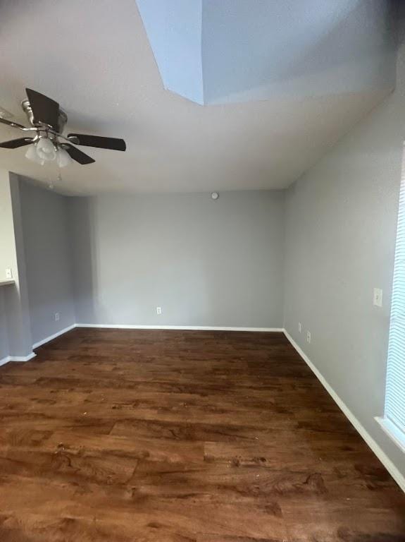 spare room with a skylight, ceiling fan, and dark wood-type flooring