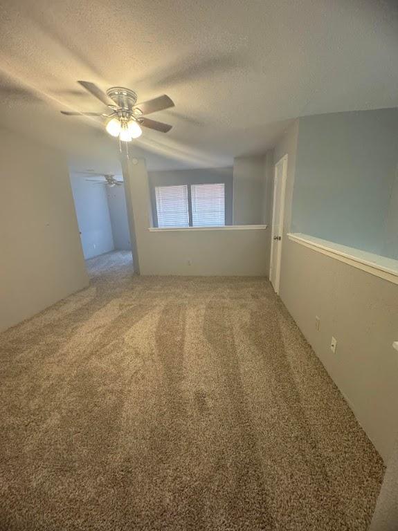 spare room featuring carpet flooring, ceiling fan, and a textured ceiling