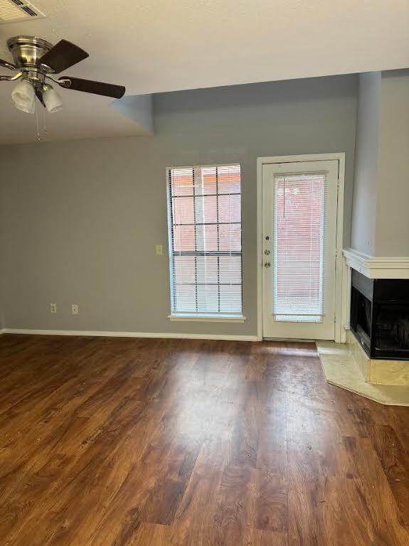 unfurnished living room featuring a multi sided fireplace, ceiling fan, and hardwood / wood-style floors