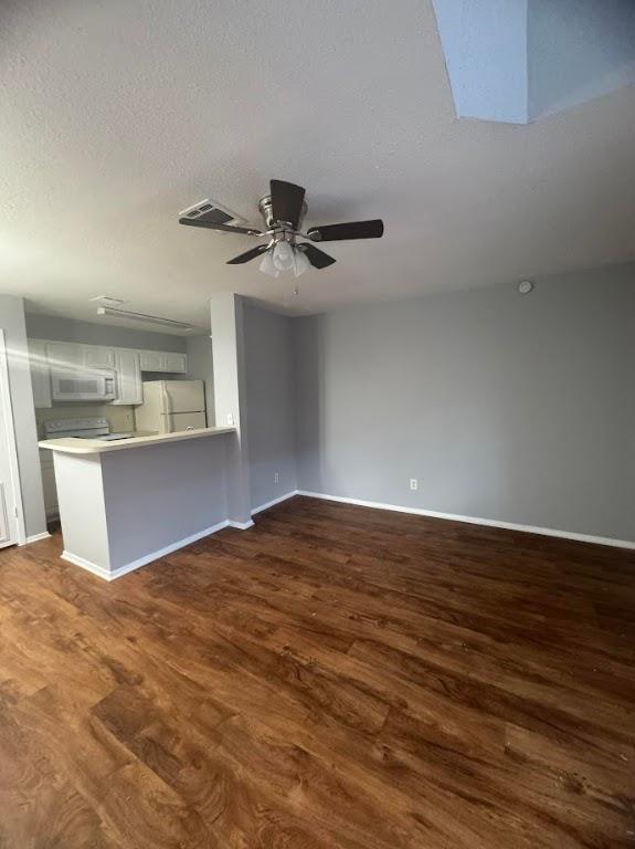 unfurnished living room featuring a textured ceiling, ceiling fan, and dark wood-type flooring