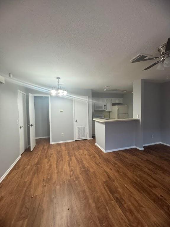 unfurnished living room featuring hardwood / wood-style flooring, ceiling fan with notable chandelier, and a textured ceiling