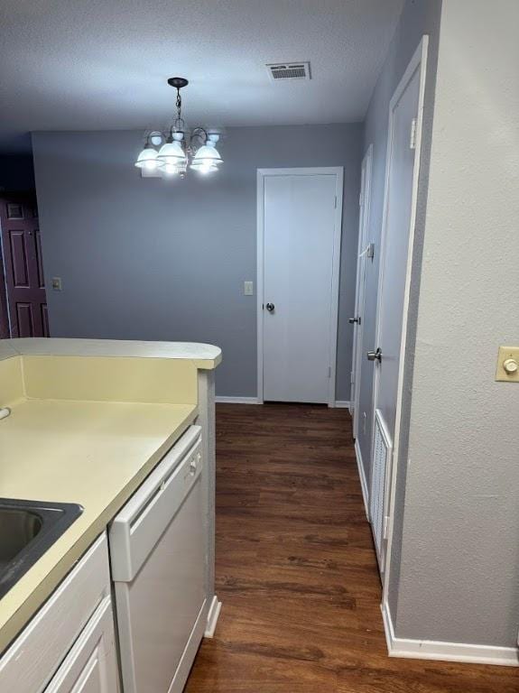 kitchen with white cabinets, dark wood-type flooring, decorative light fixtures, dishwasher, and a chandelier