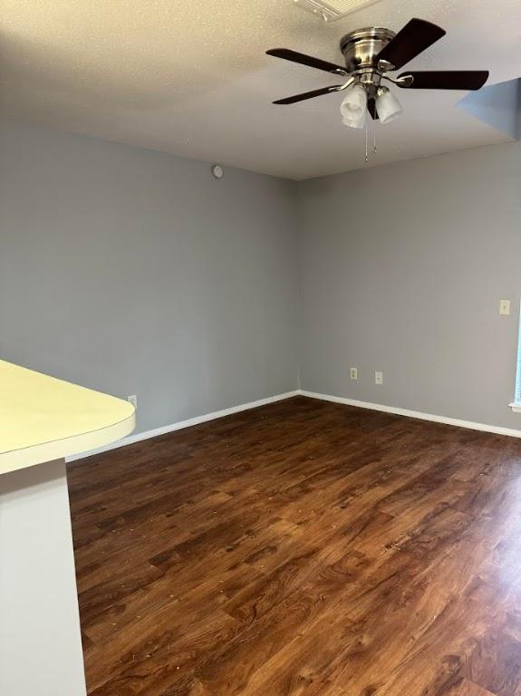 unfurnished room featuring ceiling fan and dark wood-type flooring