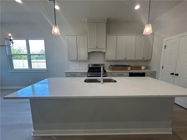 kitchen featuring hanging light fixtures, tasteful backsplash, light countertops, and a sink