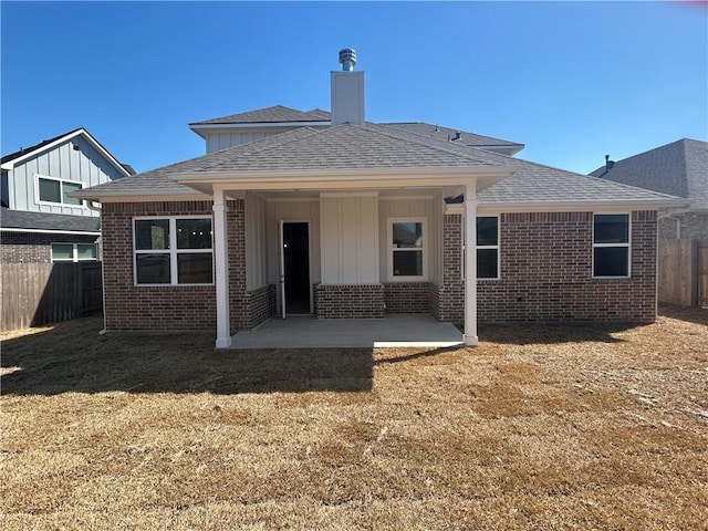 back of property with a patio, brick siding, a lawn, and fence