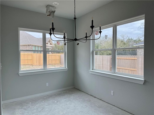 unfurnished dining area with plenty of natural light, a chandelier, and concrete flooring