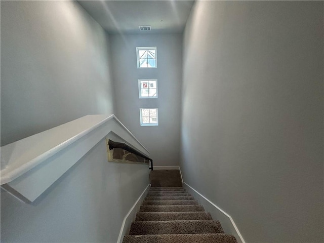 staircase featuring carpet floors, visible vents, and baseboards