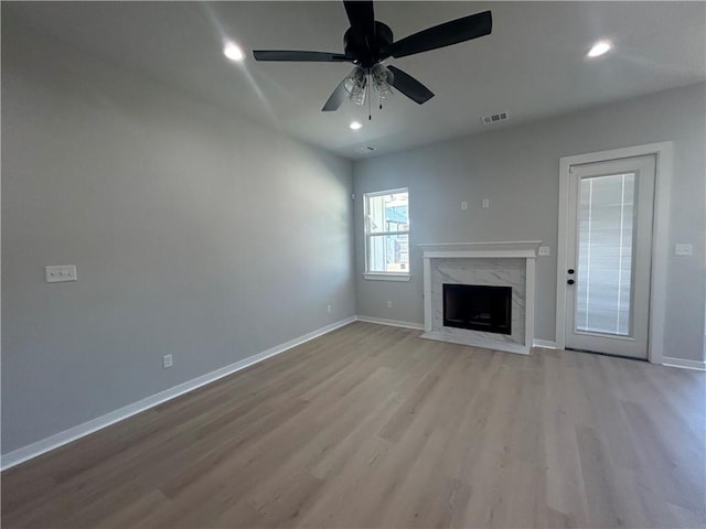 unfurnished living room with light wood-type flooring, baseboards, a fireplace, and visible vents