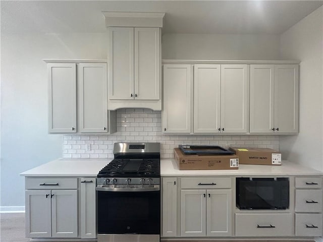 kitchen featuring white cabinets, light countertops, decorative backsplash, and gas range