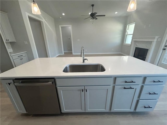 kitchen with a sink, a high end fireplace, open floor plan, dishwasher, and pendant lighting