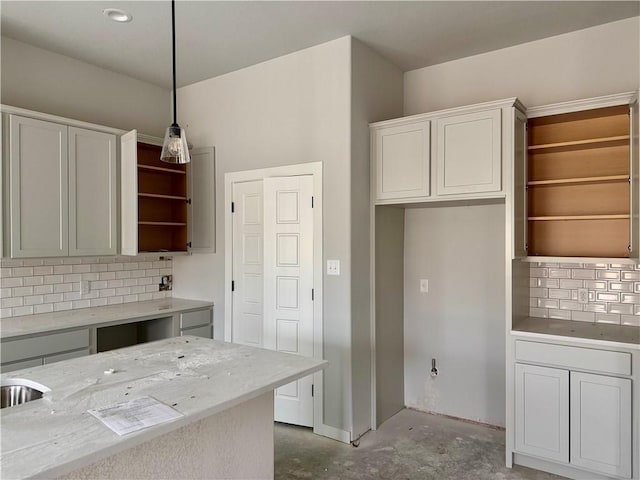 kitchen with white cabinets, backsplash, concrete flooring, and pendant lighting