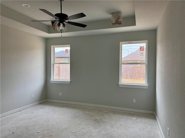 empty room featuring ceiling fan and a tray ceiling