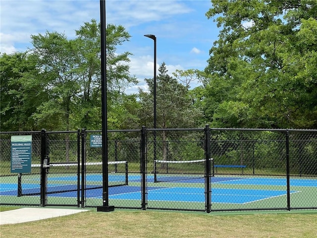 view of tennis court with a gate and fence