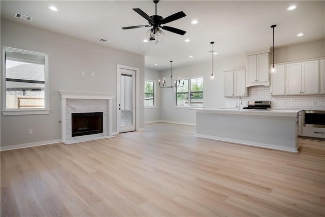 3711 Archer Falls Ct, College Station, TX 77845 - unfurnished living room with light wood-style flooring, a chandelier, baseboards, a high end fireplace, and recessed lighting
