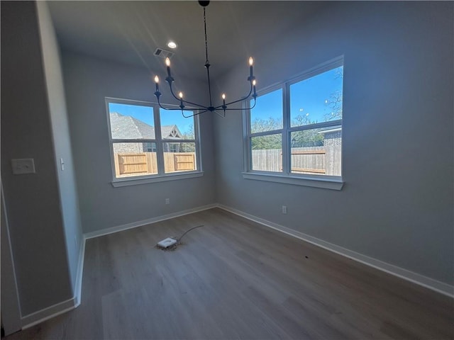 unfurnished room featuring baseboards, dark wood finished floors, visible vents, and a notable chandelier