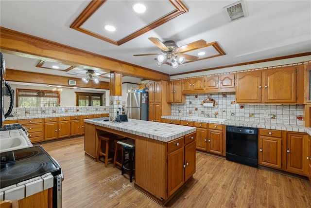 kitchen featuring stainless steel refrigerator, dishwasher, a center island, sink, and light wood-type flooring