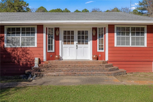 view of exterior entry with a shingled roof