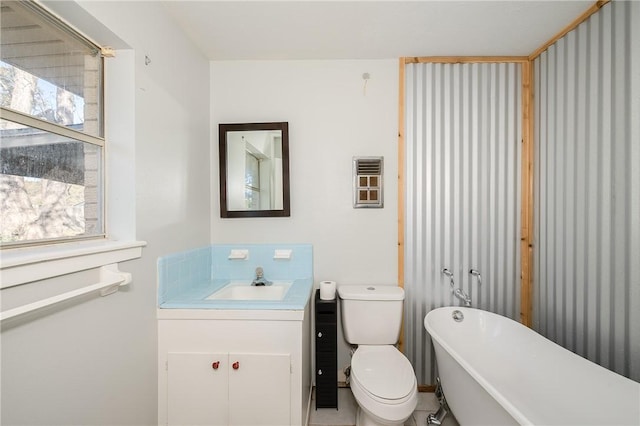 bathroom featuring tile patterned flooring, a washtub, toilet, and vanity