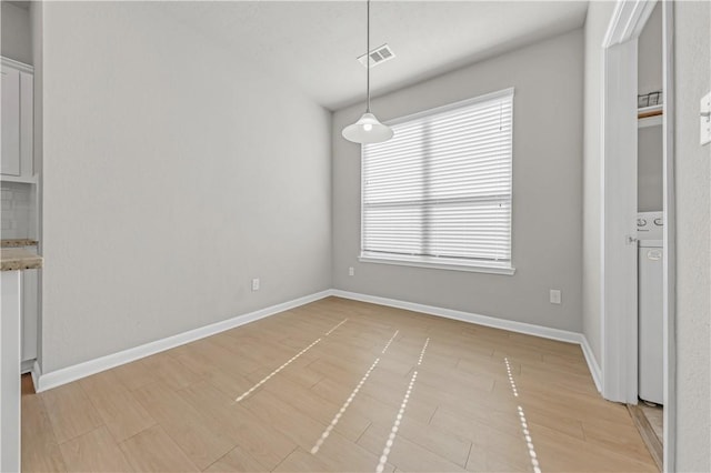 unfurnished dining area featuring visible vents, baseboards, and light wood-style flooring