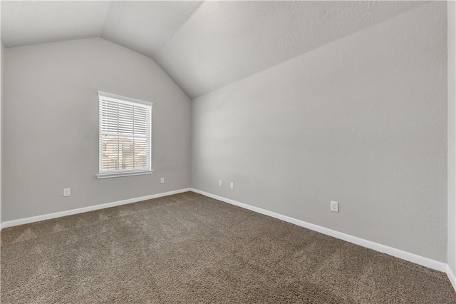 unfurnished room with baseboards, dark carpet, and vaulted ceiling