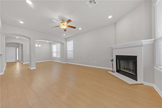 unfurnished living room featuring baseboards, visible vents, light wood finished floors, a fireplace, and ceiling fan