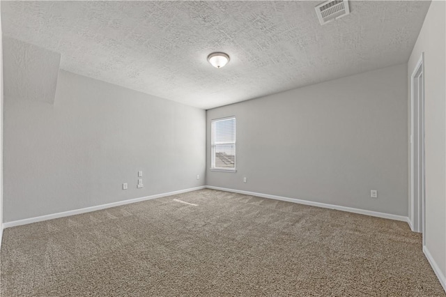 carpeted empty room featuring baseboards, visible vents, and a textured ceiling