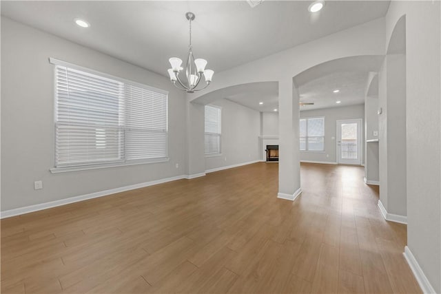 interior space with wood finished floors, recessed lighting, a fireplace, baseboards, and a chandelier