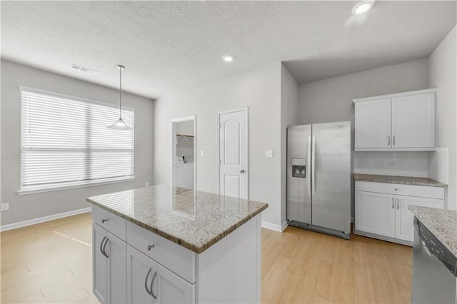 kitchen with decorative light fixtures, light wood finished floors, visible vents, and appliances with stainless steel finishes