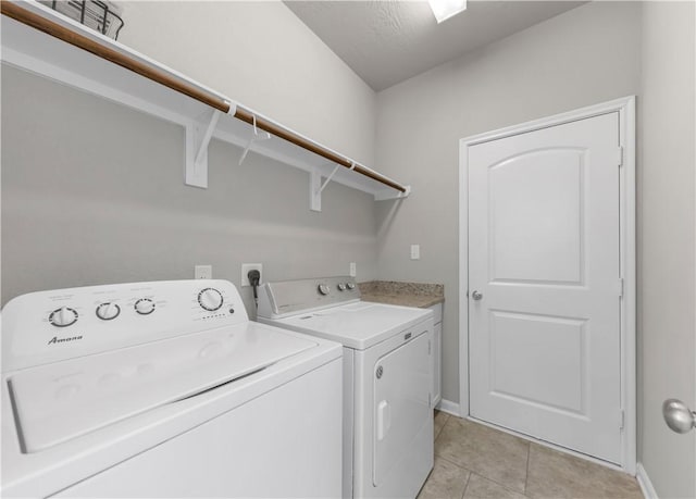 laundry room featuring washing machine and clothes dryer, light tile patterned floors, cabinet space, and baseboards