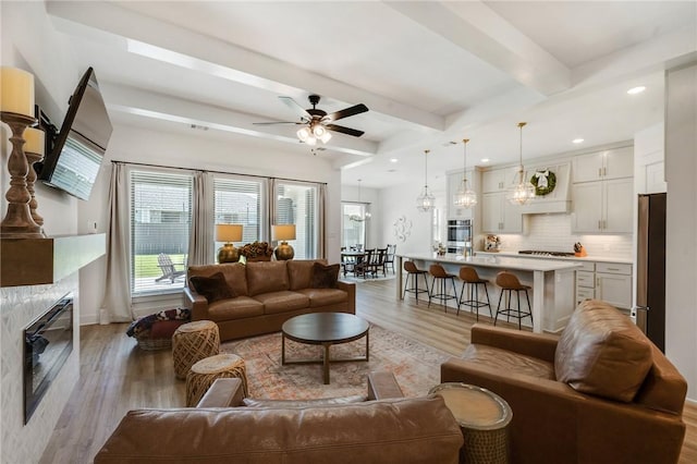 4302 Fox River Ln, Bryan, TX 77802 - living area featuring baseboards, light wood-style flooring, beamed ceiling, ceiling fan, and a premium fireplace