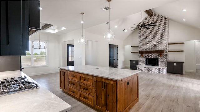 10017 Panther Creek Dr, Iola, TX 77861 - kitchen with beamed ceiling, light wood-type flooring, stainless steel gas stovetop, baseboards, and a fireplace