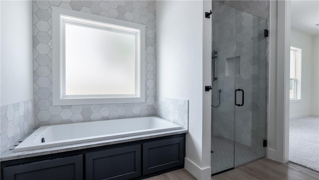 10017 Panther Creek Dr, Iola, TX 77861 - full bath featuring wood finished floors, a stall shower, a garden tub, and baseboards