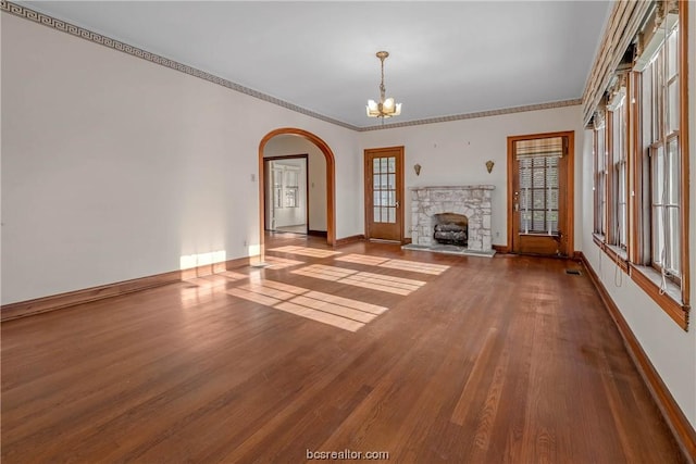 unfurnished living room featuring a chandelier, crown molding, a fireplace, and wood-type flooring