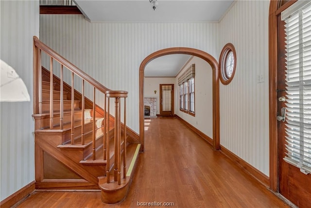 entryway with ornamental molding and hardwood / wood-style flooring