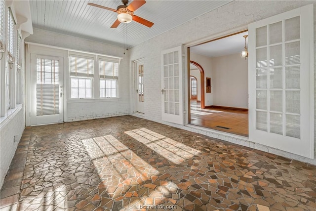 unfurnished sunroom featuring ceiling fan