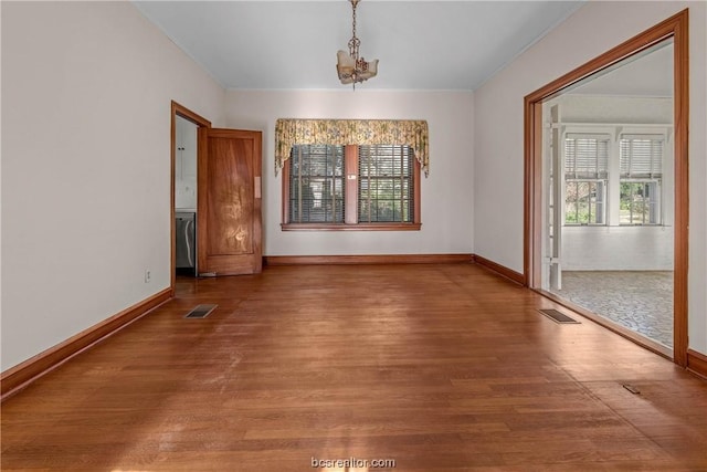 unfurnished dining area featuring ornamental molding, wood-type flooring, and an inviting chandelier