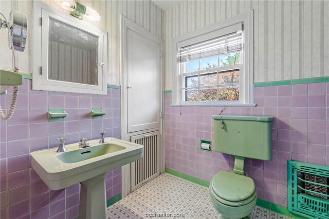 bathroom with heating unit, tile patterned floors, and tile walls