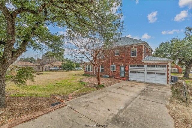 view of front of property with a front lawn, central AC unit, and a garage