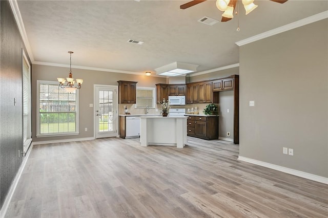 kitchen featuring white appliances, visible vents, open floor plan, light countertops, and a center island