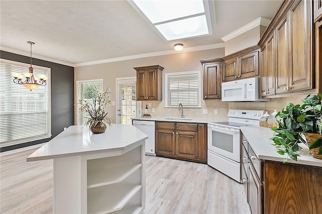 kitchen with white appliances, brown cabinets, light countertops, light wood-type flooring, and a sink