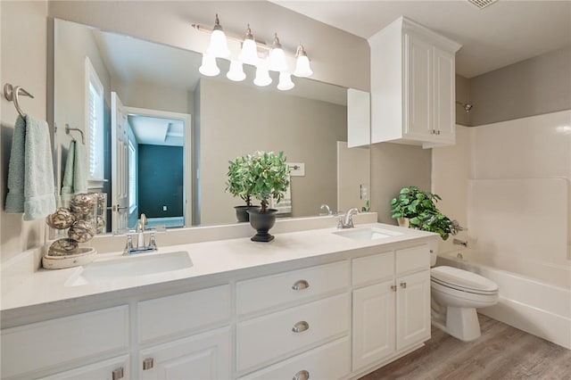 bathroom with double vanity, wood finished floors, shower / bath combination, and a sink