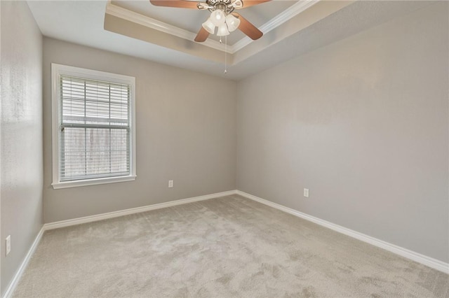 spare room with ornamental molding, a raised ceiling, light carpet, and baseboards