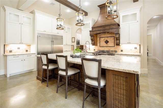 kitchen featuring custom range hood, a sink, finished concrete flooring, arched walkways, and built in appliances