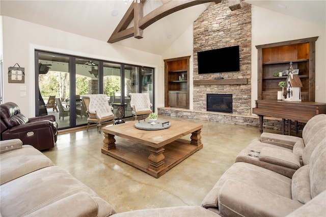 living area featuring built in shelves, high vaulted ceiling, a stone fireplace, and finished concrete flooring