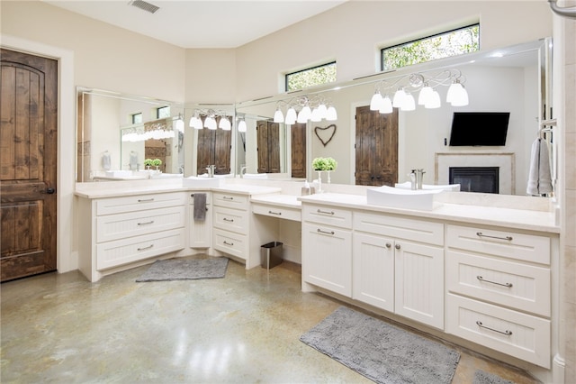 bathroom with visible vents, concrete floors, a glass covered fireplace, and vanity