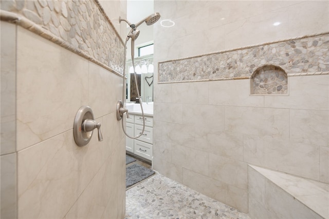 full bathroom with tile walls, vanity, and a tile shower